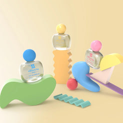 Flacons Olfazeta by Chogan Baby, bouchons bleu, jaune et rose, parmi des formes pastel ludiques