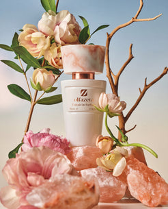 Flacon blanc Olfazeta by Chogan Millésime N°10 sur roches de sel rose parmi roses pâles et branches nues