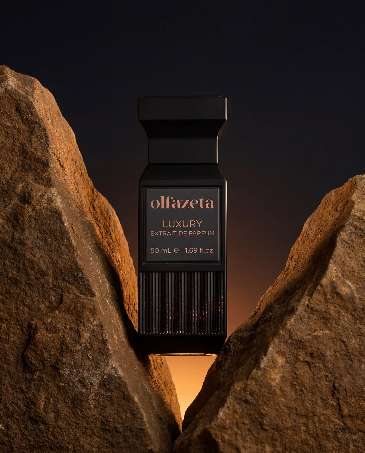 Flacon noir Olfazeta by Chogan Luxury N°74 dressé entre deux rochers ocre au coucher de soleil